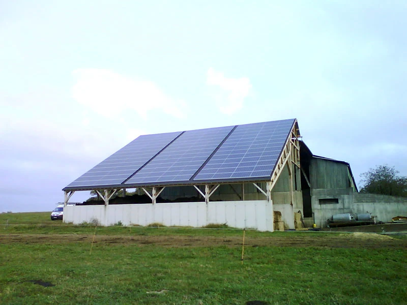 Scène extérieure rurale avec bâtiment agricole équipé d'installation solaire photovoltaïque sur toiture inclinée