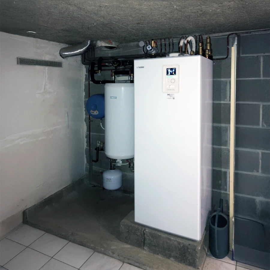 Cave technique avec chaudière à condensation murale blanche de marque NIBE installée sur mur en parpaings