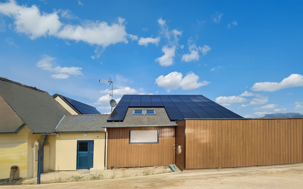 Maison résidentielle avec extension moderne en bardage bois sous ciel bleu nuageux