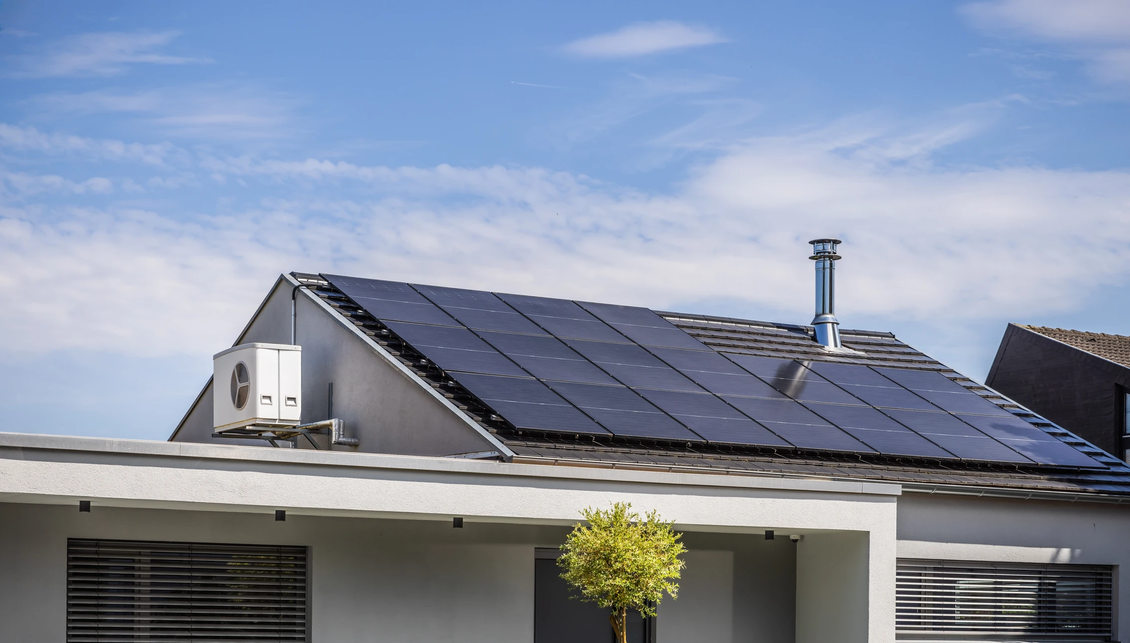 Vue a&eacute;rienne d'un b&acirc;timent commercial &eacute;quip&eacute; de panneaux solaires photovolta&iuml;ques sur toiture bleue ondul&eacute;e, au coucher du soleil